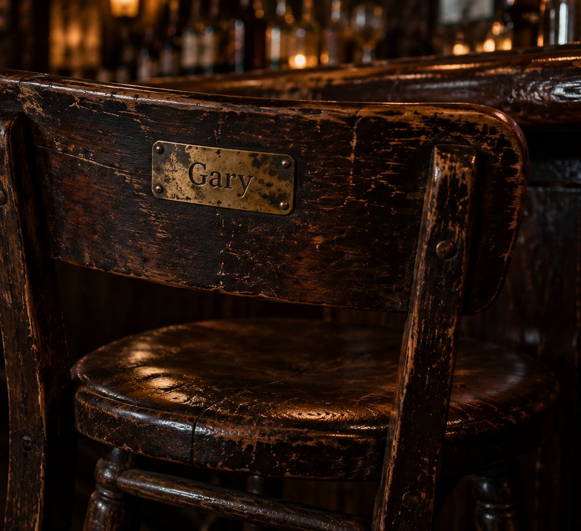 An empty, worn wooden bar stool with a brass nameplate reading Gary